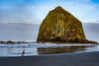 A man running on the wet sand beach withe Haystack Rock and the Needles in the background, Canon Beach, Oregon