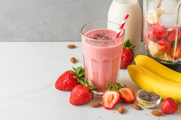 Wall Mural - Glass of strawberry and banana vegan smoothie or milkshake made of almond milk with fresh juicy ingredients in blender