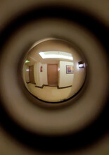 A Corridor, Lamps, A Floor And Two Neighboring Doors Are Visible In The Door Peephole