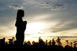 © buraratn - silhouette of a woman asking for blessings from God Evening sun background