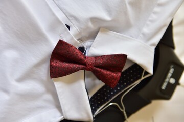 Poster - Closeup shot of a red bow tie on a white shirt under the lights - fashion concept