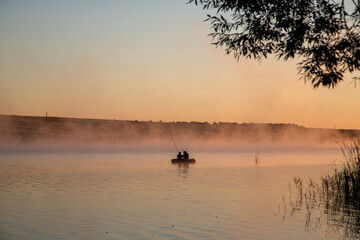 silhouettes of two fishermen in a boat at sunrise