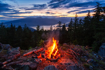 warm camp fire on top of a mountain with beautiful canadian nature landscape in background during a 