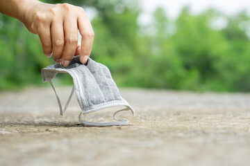  woman hand picking up dirty,used  face mask on the ground