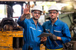 © Thirawatana - Mechanic holding a wrench and a tablet standing in front of an industrial forklift. Engineers and skilled technicians are looking forward.