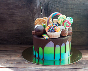 Wall Mural - Bright birthday green and blue colored cake decorated with chocolate, cake pops, lollipop, waffle and cupcake.