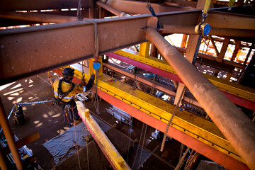 Industrial rope access rigger miner worker wearing safety harness, helmet working at height abseiling on twin ropes using 3 tone chain block to lifting load construction mine site Perth Australia 
