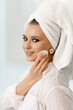 © ANR Production - Cute young attractive woman with a towel on her head doing morning facial skin care procedures. The girl removing makeup and cleanses her face. Healthy lifestyle concept.