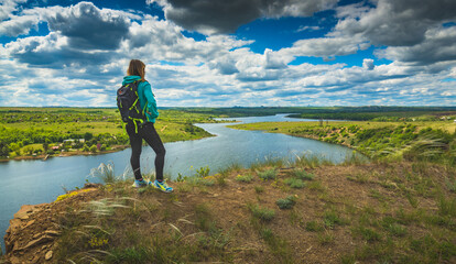 Wall Mural - Girl hiker on a hill over the river