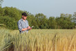 © Taras Rudenko - male agronomist in cap takes notes in a notebook on a green agricultural field of wheat