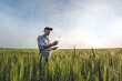 © Taras Rudenko - male agronomist in cap takes notes in a notebook on a green agricultural field of wheat