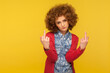 Don't bother me! Portrait of rude vulgar woman with curly hair showing middle fingers, impolite gesture of disrespect, looking with aggression hate. indoor studio shot isolated on yellow background