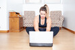 © Guaraciaba - modern life. Plus size woman sitting on the floor preparing to start her online gym class at home.   at home.