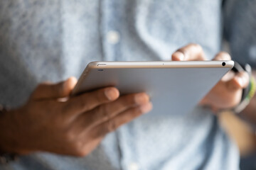 Close up hands African man holding digital tablet device. E-commerce websites buy in internet on-line stores usage, typing e-mail to client, reading sending message to friends, e-date website concept