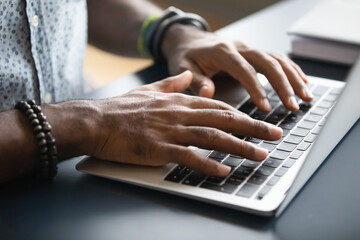close up image african male hands typing on laptop keyboard. businessman answer on client e-mail, cu