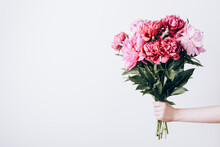 Female Hand Holds Beautiful Bouquet Of Peonies. Flower Delivery Concept