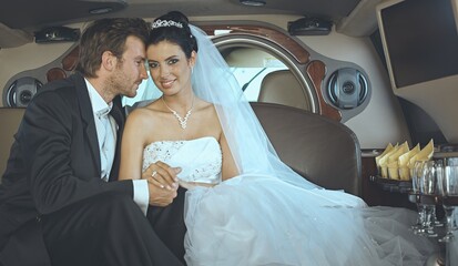 Wedding couple on marriage day together in luxury limousine embracing and having fun. 