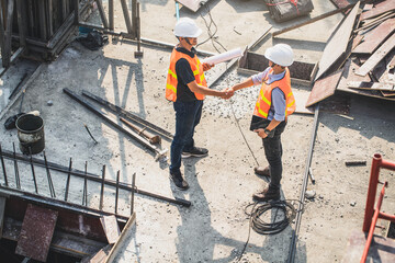 Hanshake seals an agreement at construction site. Architect and worker handshaking on construction site. building, teamwork, partnership, gesture and people concept.