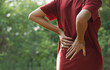 © mintra - Closeup hands of woman touching her back pain in healthy concept on nature background.