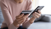 Close Up Female Hands Holding Credit Card And Smartphone, Young Woman Paying Online, Using Banking Service, Entering Information, Shopping, Ordering In Internet Store, Doing Secure Payment