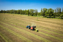 Small Tractor With Round Baler Unloading On A Field