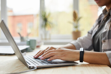 Wall Mural - Side view close up of young mixed-race woman using laptop while working at home office, hands typing on keyboard, copy space