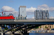 Stadtansicht am Berliner Hauptbahnhof mit Blick auf einen ausfahrenden Zug auf einer Brücke über den Humboldthafen mit Hochhäusern im Hintergrund