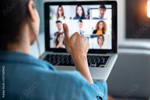 Fotomural Business woman making video call and showing thumb up to laptop on the online briefing while sit on sofa at home