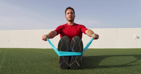 Wall Mural - Fitness man training shoulders back and arms with resistance bands at outdoor gym. Body workout with equipment outside. Elastic rubber band accessory. Slow motion 59.94 fps. See other exercises.