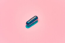 Creative Concept With Blue Glitter Pill Isolated On Pastel Pink Background. Minimal Style, Art Concept