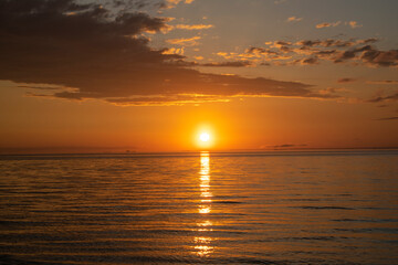 Sunset in the evening on the lake. Clouds and the setting sun. Little waves. Romantic setting.