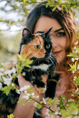  Girl and cat. Spring or summer warm weather concept. Bokeh background. Ginger kitten with two face color mask.