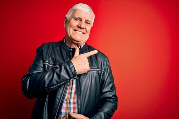 Wall Mural - Senior handsome hoary man wearing casual shirt and jacket over isolated red background cheerful with a smile of face pointing with hand and finger up to the side with happy and natural expression