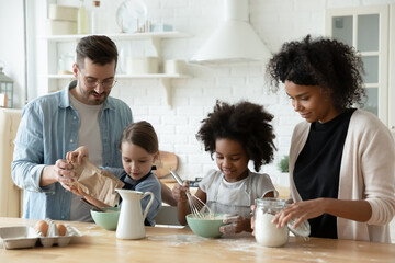 Wall Mural - Multi racial full family cooking pastries gathered together in kitchen mixing products fresh ingredients eggs flour and milk make dough preparing holiday cake. Lifestyle, parenthood, cookery concept