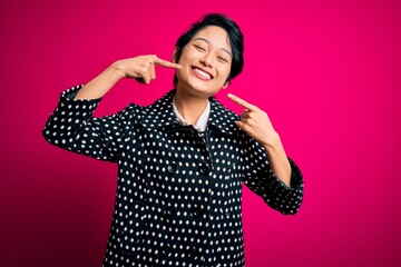 Wall Mural - Young beautiful asian girl wearing casual jacket standing over isolated pink background smiling cheerful showing and pointing with fingers teeth and mouth. Dental health concept.