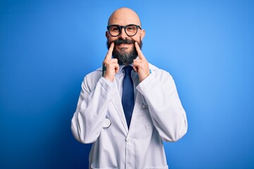 Sticker - Handsome bald doctor man with beard wearing glasses and stethoscope over blue background Smiling with open mouth, fingers pointing and forcing cheerful smile