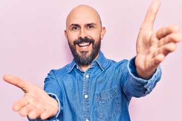 Sticker - Young handsome man wearing casual clothes looking at the camera smiling with open arms for hug. cheerful expression embracing happiness.