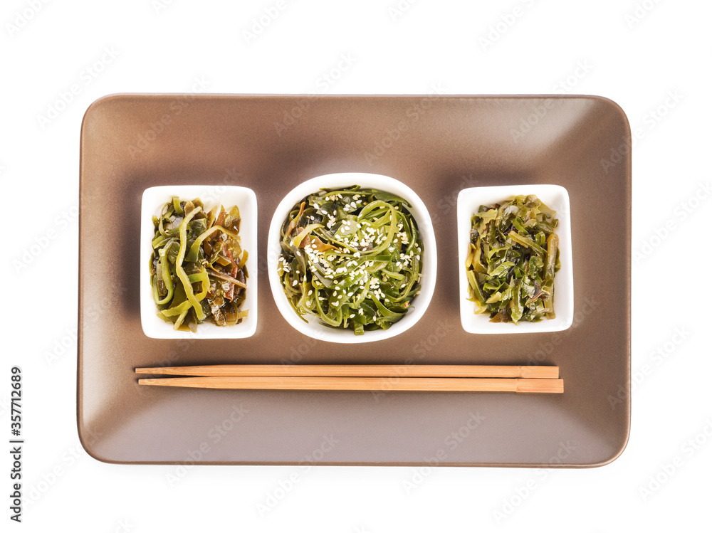 Bowls with tasty seaweed and chopsticks on white background