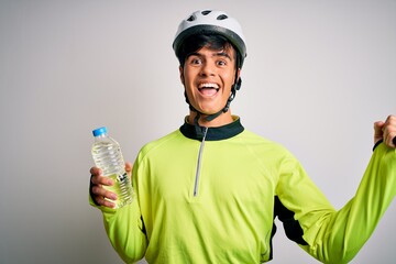 Poster - Young handsome cyclist man wearing security bike helmet drinking bottle of water screaming proud and celebrating victory and success very excited, cheering emotion