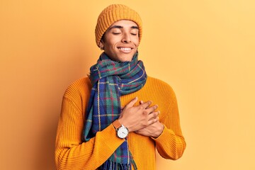 Sticker - Young african amercian man wearing casual winter clothes smiling with hands on chest with closed eyes and grateful gesture on face. health concept.