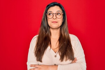 Sticker - Young hispanic smart woman wearing glasses standing over red isolated background smiling looking to the side and staring away thinking.