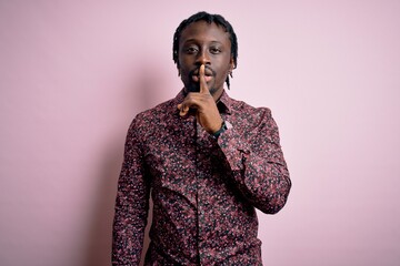 Poster - Young handsome african american man wearing casual shirt standing over pink background asking to be quiet with finger on lips. Silence and secret concept.