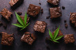 Chocolate cannabis brownies on dark background with marijuana leaf made with CBD butter. A delicious desert to impress your dinner guests and a relaxing way to end the evening.