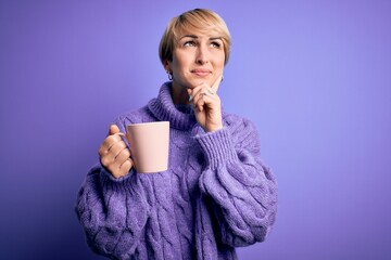 Sticker - Young blonde woman with short hair wearing winter sweater drinking a cup of hot coffee serious face thinking about question, very confused idea