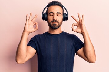 Sticker - Young hispanic man listening to music using headphones relax and smiling with eyes closed doing meditation gesture with fingers. yoga concept.