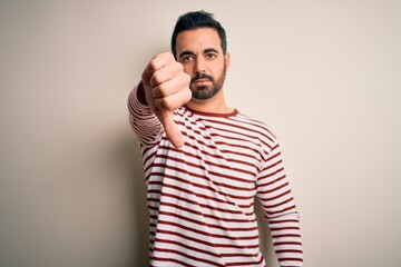 Canvas Print - Young handsome man with beard wearing casual striped t-shirt standing over white background looking unhappy and angry showing rejection and negative with thumbs down gesture. Bad expression.