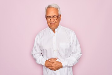 Sticker - Middle age senior grey-haired man wearing glasses and business shirt over pink background with hand on stomach because indigestion, painful illness feeling unwell. Ache concept.