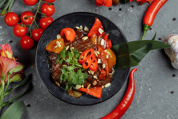 Beef wok. Traditional chinese mongolian beef stir fry in chinese cast iron wok with cooking chopsticks, stone slate background. Top view, copy space