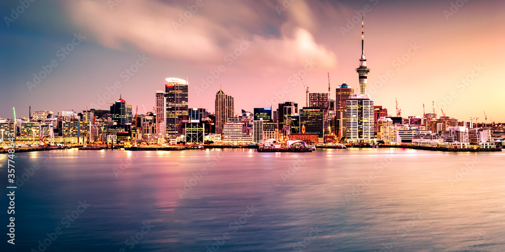 Panoramic view of Auckland city skyline and harbour at sunset as seen from the North Shore. Auckland is known as the "City of Sails" and will host the America's  Cup in 2021.     - obrazy, fototapety, plakaty 