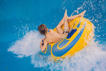 Boy On A Pool Float On Artificial Waves In A Water Park